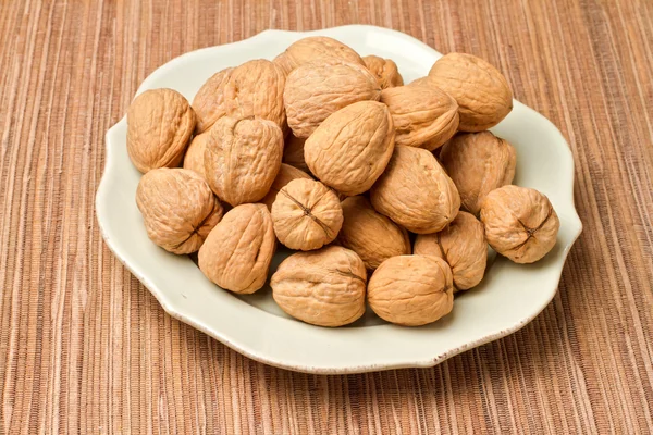 Plate with walnuts on tablecloth — Stock Photo, Image