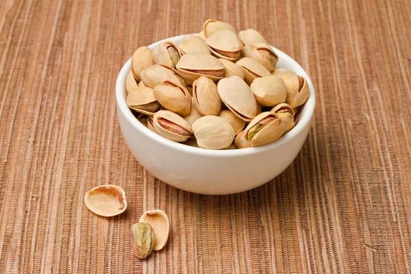 Pistachios nuts in bowl over tablecloth — Stock Photo, Image