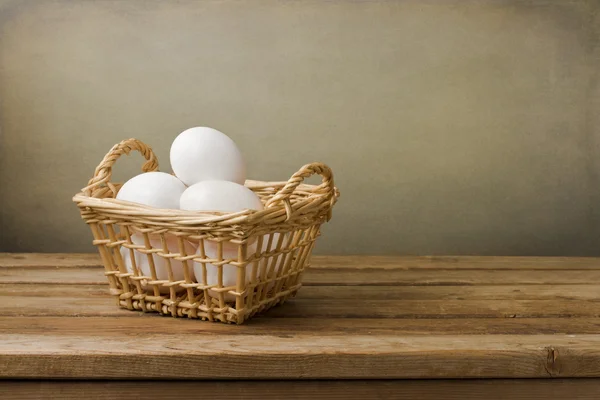Ovos na cesta na mesa de madeira — Fotografia de Stock