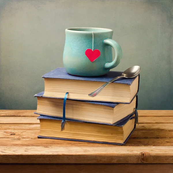 Alte Bücher und Tasse mit Herzform auf Holztisch — Stockfoto