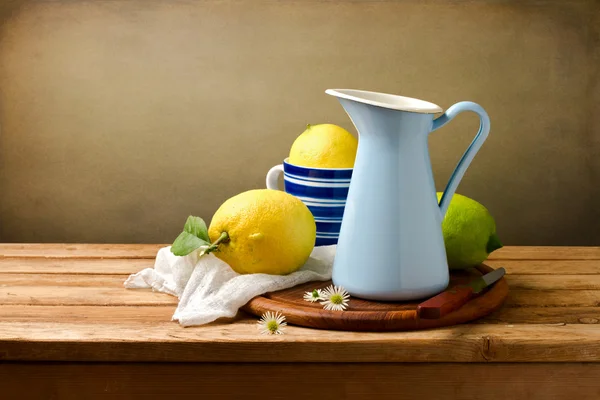 Still life ith lemons and blue enamel jug on wooden table — Zdjęcie stockowe