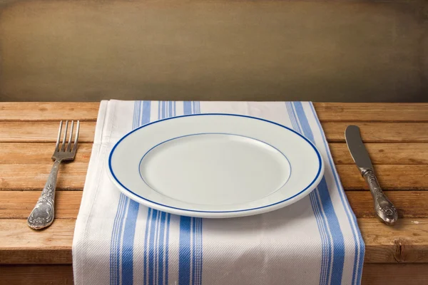 Empty plate with fork and knife on tablecloth — Stock Photo, Image