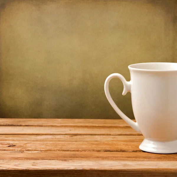 Hintergrund mit weißer Tasse auf Holztisch über Grunge-Wand — Stockfoto