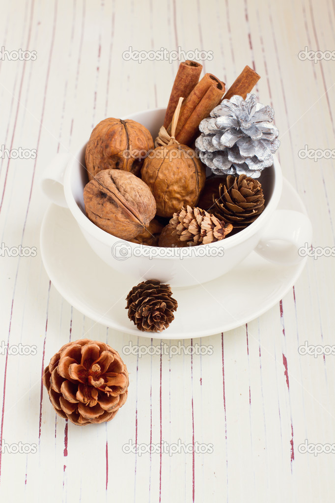 Walnuts and Christmas decor in cup on white tabletop