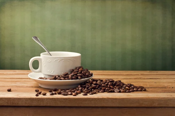 Coffee cup with coffee beans on wooden table — Stock Photo, Image