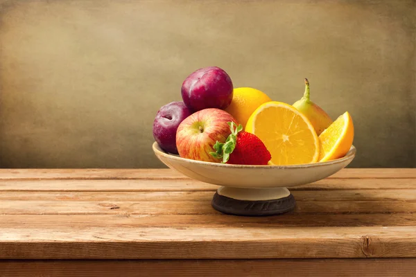 Vaas met vers fruit op houten tafel — Stockfoto