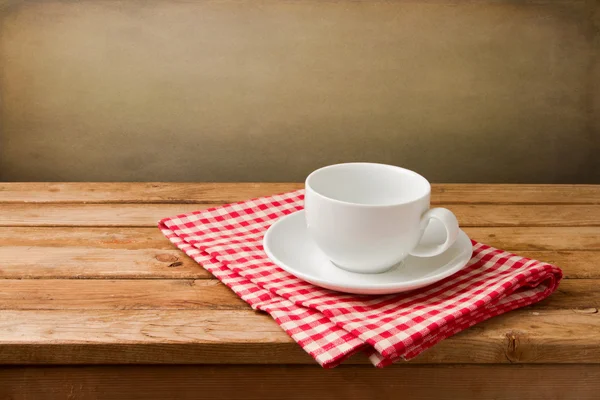 Empty coffee cup on tablecloth on wooden table — Stock Photo, Image