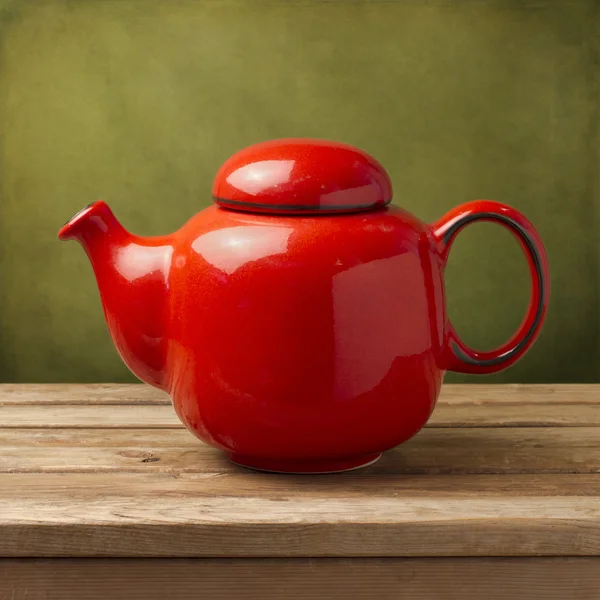 Red tea pot on wooden table over green grunge wall — Stock Photo, Image