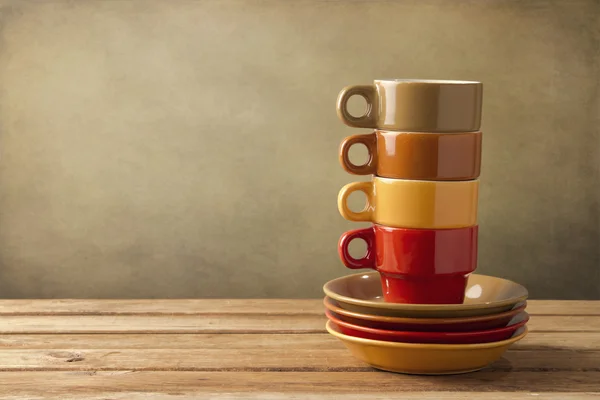 Färgglada Kaffekoppar och tallrikar på träbord — Stockfoto