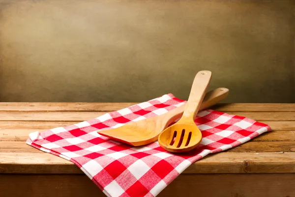 Kitchen utensils on tablecloth on wooden table — Stock Photo, Image