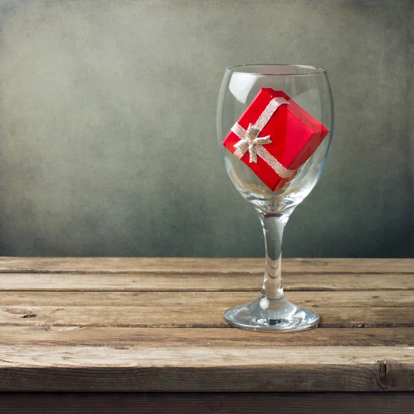 与红色礼品盒木制桌上的红酒杯 — 图库照片