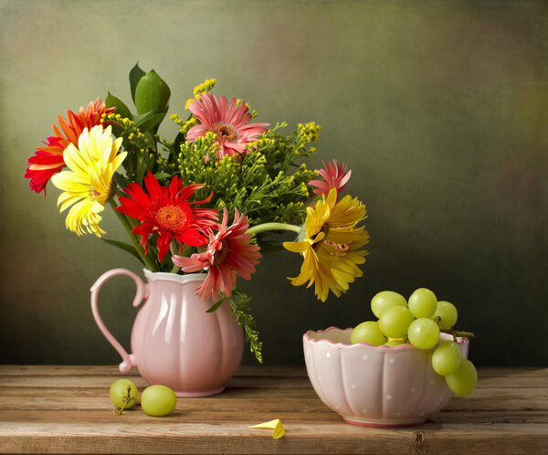 Still life with beautiful flower bouquet and green grapes