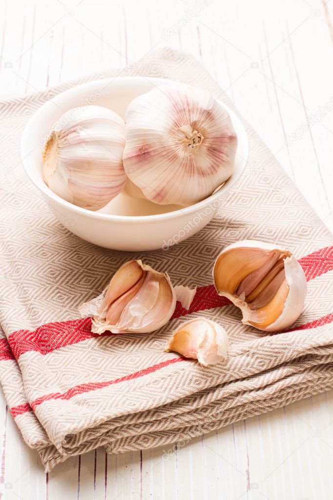Garlic in white dish on white wooden tabletop