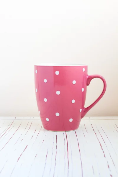 Polka dots cup on white wooden table — Stock Photo, Image