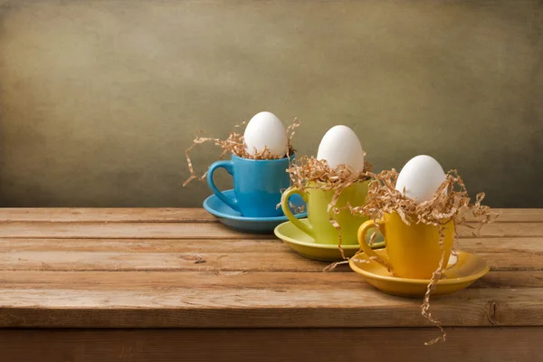 Фон с пасхальными яйцами в кофейных чашках — стоковое фото