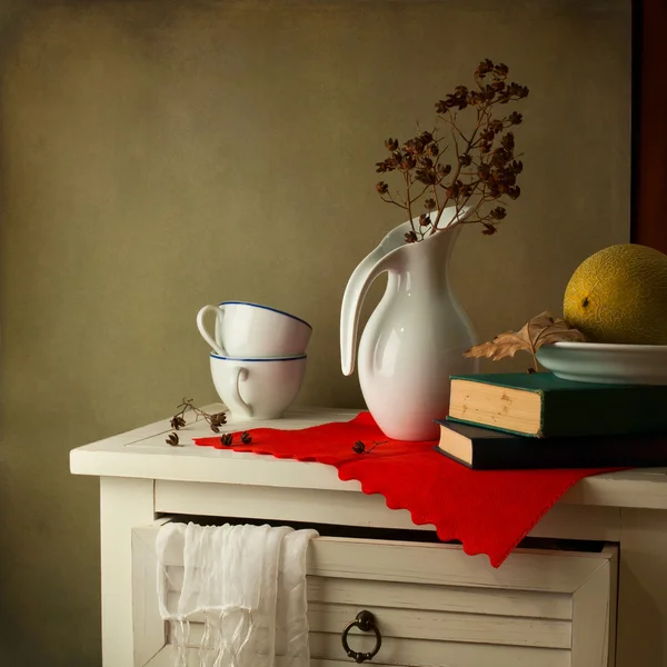 Csendélet a kancsót, a könyvek és a görögdinnye, a fehér asztal — Stock Fotó