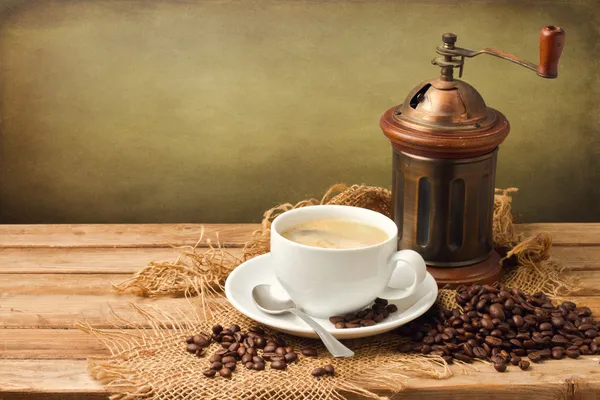 Старинная кофемолка и чашка кофе — стоковое фото