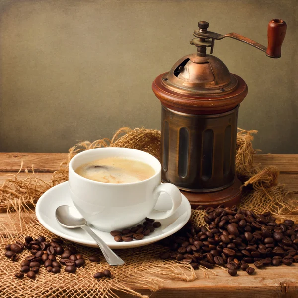 Filiżanka kawy z rocznika młynek na drewnianym stole — Zdjęcie stockowe