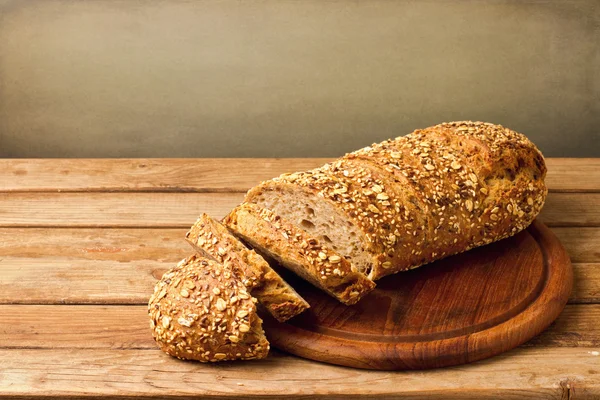 Fresh bread on wooden board over grunge background — Stock Photo, Image