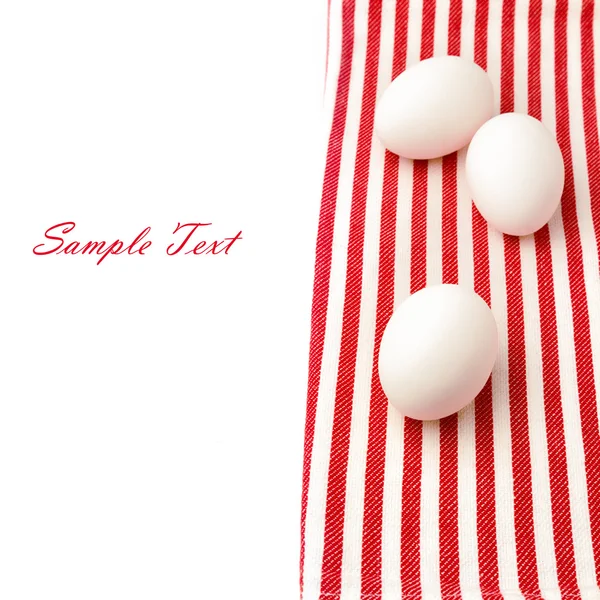 White eggs on red tablecloth over white background — Stock Photo, Image