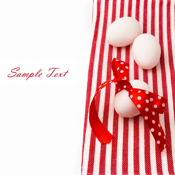 White eggs with polka dots ribbon on red tablecloth — Stock Photo, Image