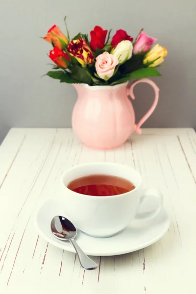 Kopp te på träbord med rosa blommor — Stockfoto