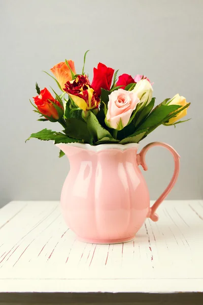 Rose flowers in pink jug on wooden table — Stock Photo, Image