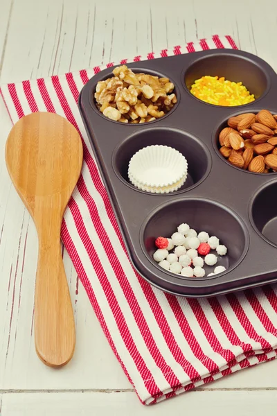 Cupcake ingredients in oven tray over red striped tablecloth — Stock Photo, Image