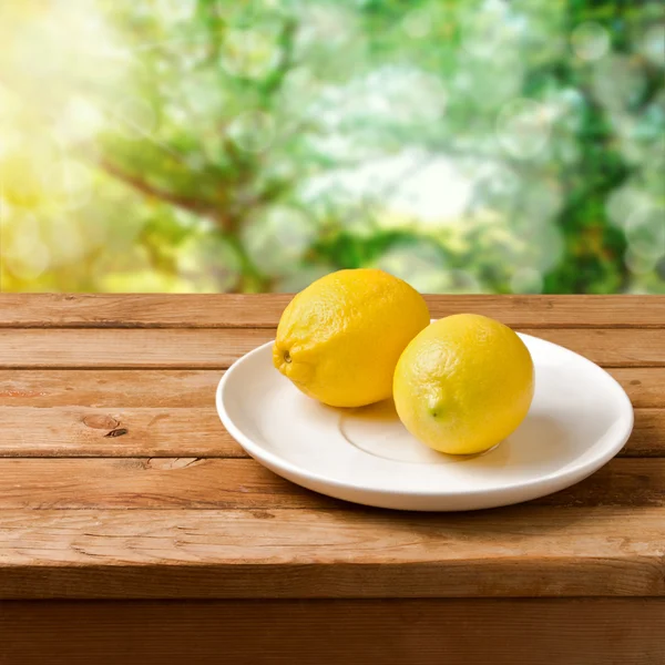 Frische Zitronen auf Teller über Bokeh Hintergrund — Stockfoto