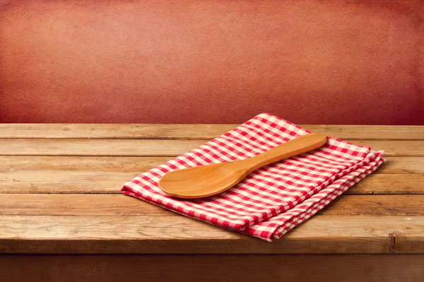 Wooden table with tablecloth and spoon — Stock Photo, Image