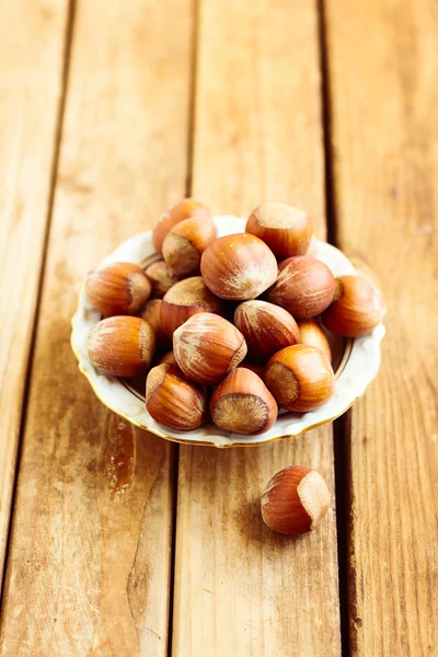 Hazelnuts on plate over wooden background — Stock Photo, Image