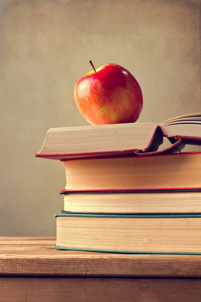 Books and apple on wooden table — Stock Photo, Image