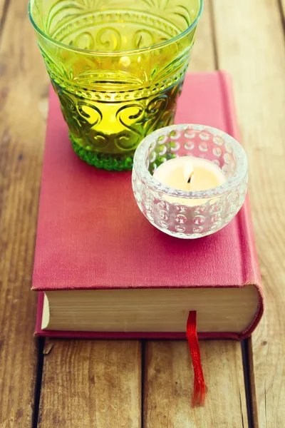 Decoratieve kaarsen op boek over houten achtergrond — Stockfoto