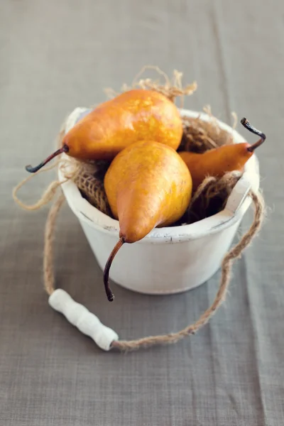 Brown pears in wooden bucket over textile background — Stock Photo, Image