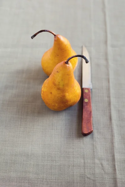 Bruna päron med kniv över textil bakgrund — Stockfoto