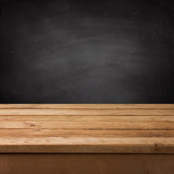 Empty wooden deck table over chalkboard — Stock Photo, Image