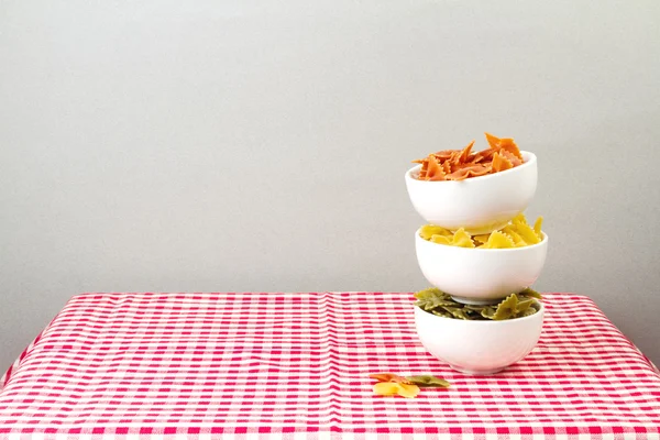 Pasta farfalle i skålar på röd bordsduk — Stockfoto
