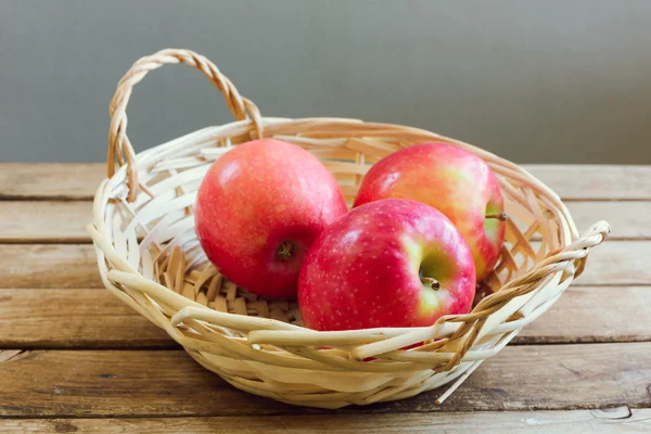 Pommes rouges dans le panier sur la table de pont en bois — Photo