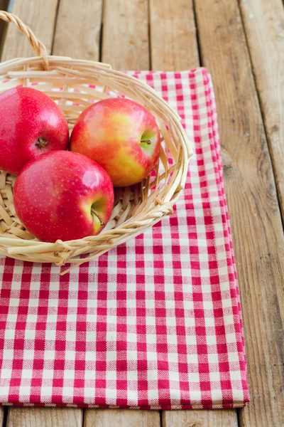 Röda äpplen i korgen på duken — Stockfoto