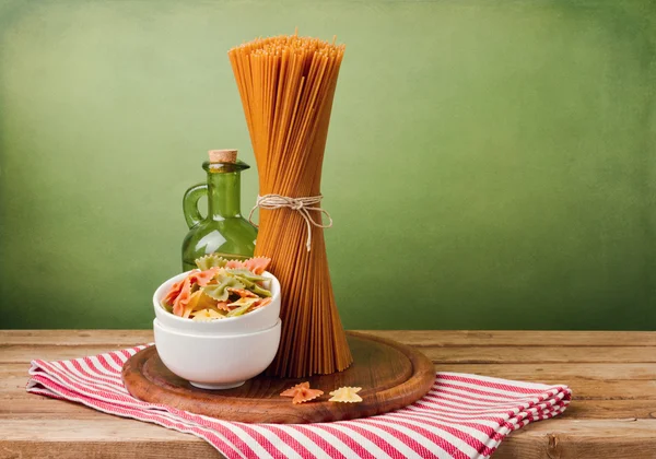 Fullkornsvete spaghetti och farfalle pasta på träbord. — Stockfoto