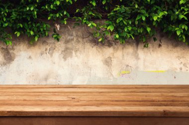 Wooden deck table over urban wall with leaves clipart