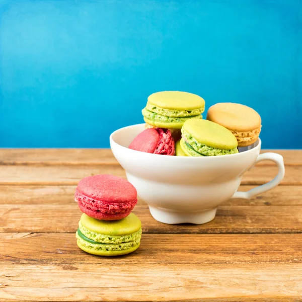 Macaroons in coffee cup on wooden table — Stock Photo, Image