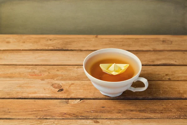 Tea cup with paper origami boat — Stock Photo, Image