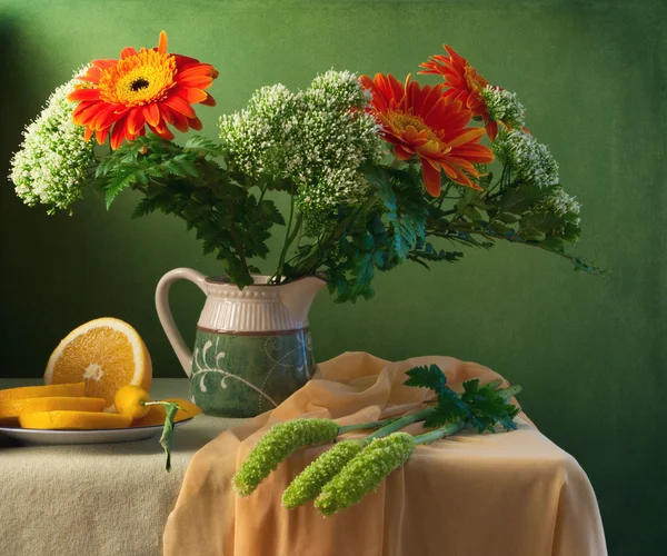 Bodegón con flores y naranja sobre fondo verde — Foto de Stock