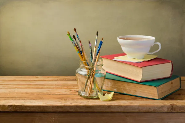 Libros antiguos, taza de té y pinceles para pintar — Foto de Stock
