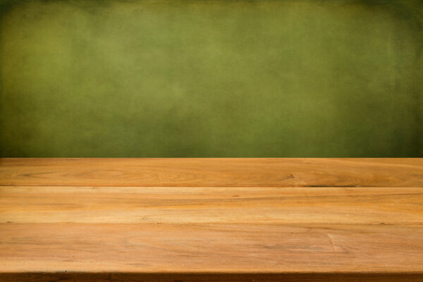 Empty wooden table over grunge green background.