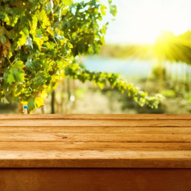 Empty wooden deck table over vineyard bokeh background clipart