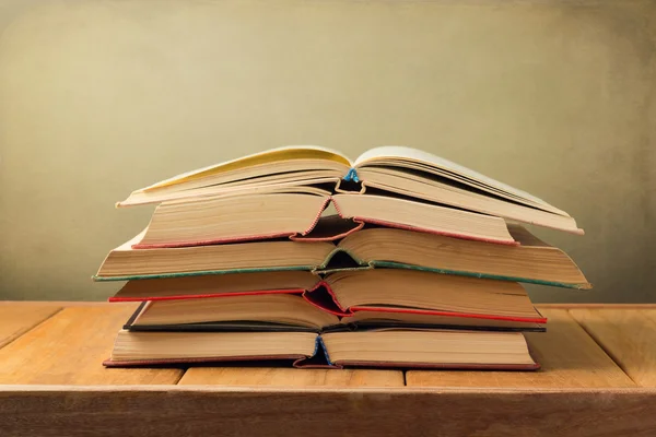 Stos otwarte starych książek na drewnianym stole w tło grunge — Zdjęcie stockowe