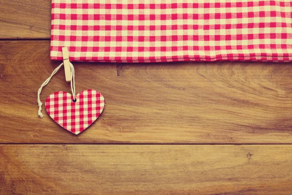 Retro toned background with checked tablecloth and heart shape on wooden board — Stock Photo, Image