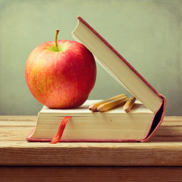 Libro viejo y manzana sobre mesa de madera sobre fondo grunge. Regreso al concepto escolar Fotos de stock libres de derechos